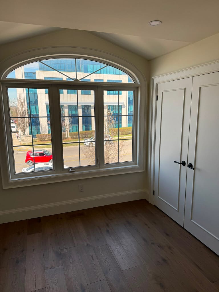 Finished Vaughan bedroom with custom interior doors, black hardware, window casing, baseboards, and hardwood flooring.