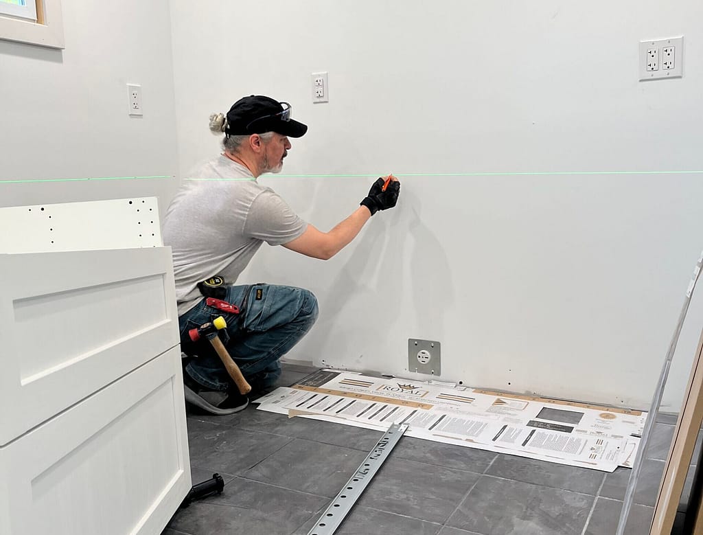 finish carpenter installs a kitchen cabinet in an Oakville house