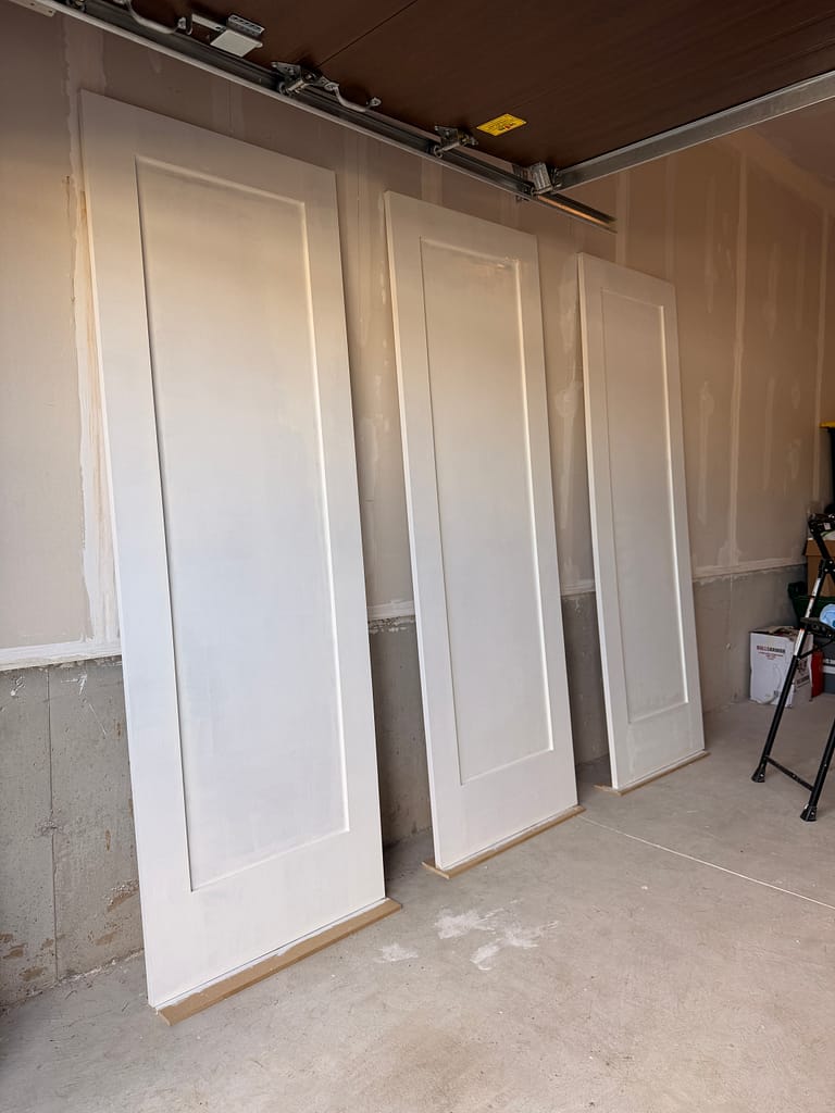 Primed custom closet doors prepared for installation in a Hamilton condo